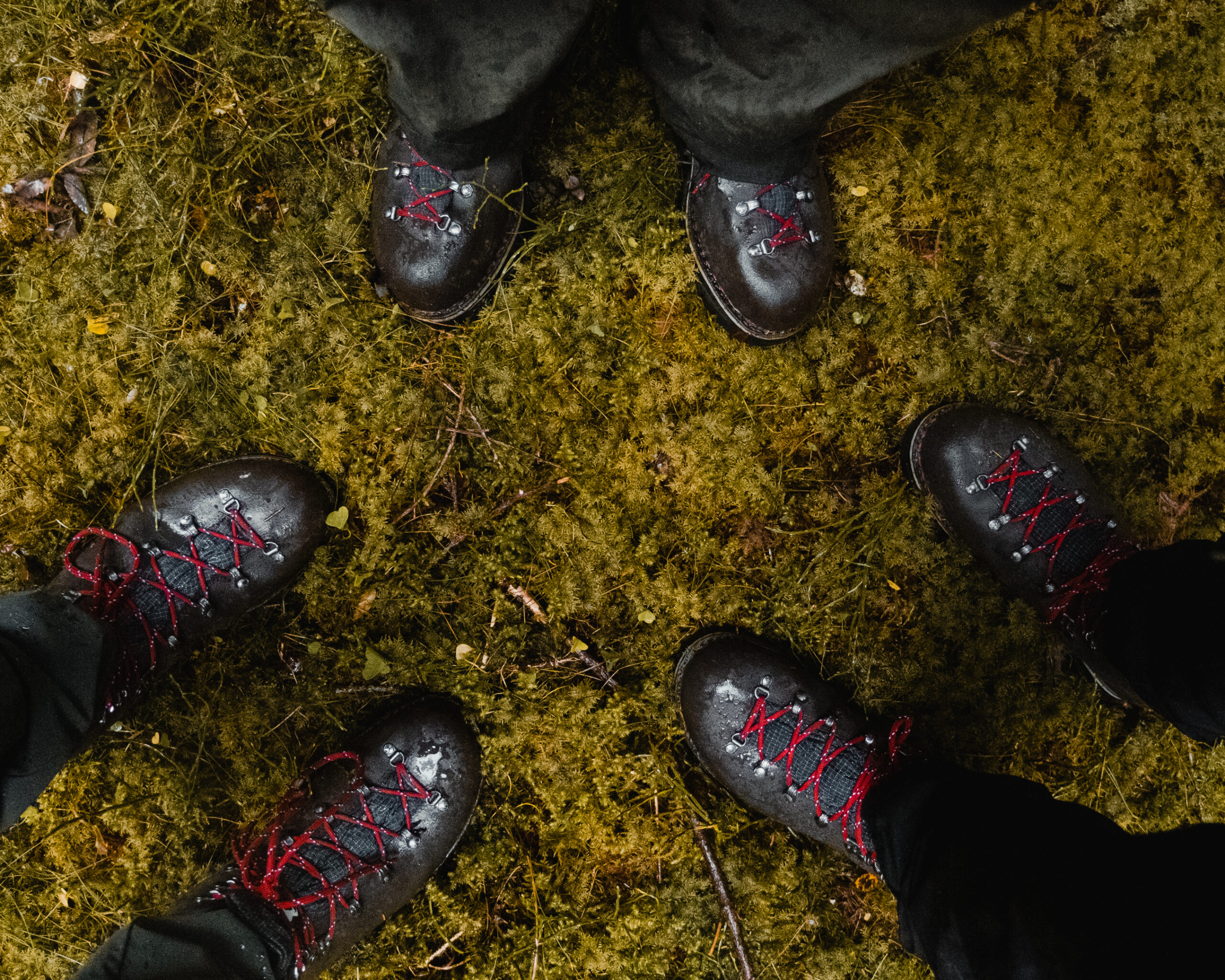 Super Rando range seen from above (flatlay) of three pairs of Galibier mountain boots. Detail on the full-grain leather, the Norwegian welt, and the technical red laces. Outdoor setting on natural terrain.