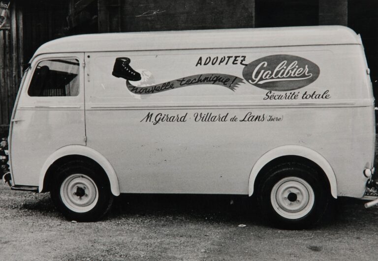 Photographie en noir et blanc d'une ancienne camionnette publicitaire de la marque Galibier. Le véhicule affiche les mentions "Adoptez Galibier", "Nouvelle technique", "Sécurité totale" et le nom du distributeur M. Girard à Villard-de-Lans en Isère.