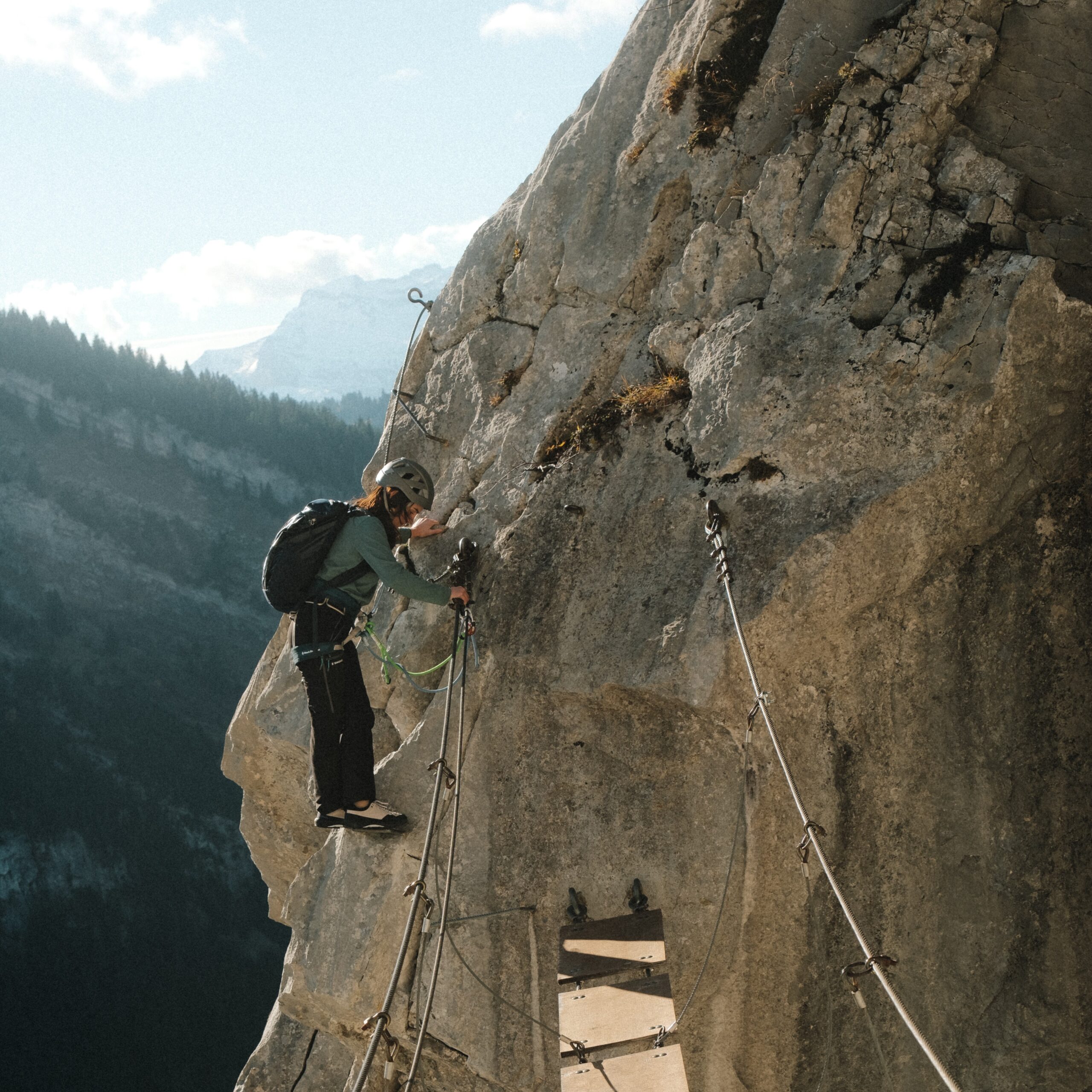 Gros plan sur des chaussures de randonnée en cuir marron avec membrane Sympatex et semelle crantée sur un sentier rocheux humide.