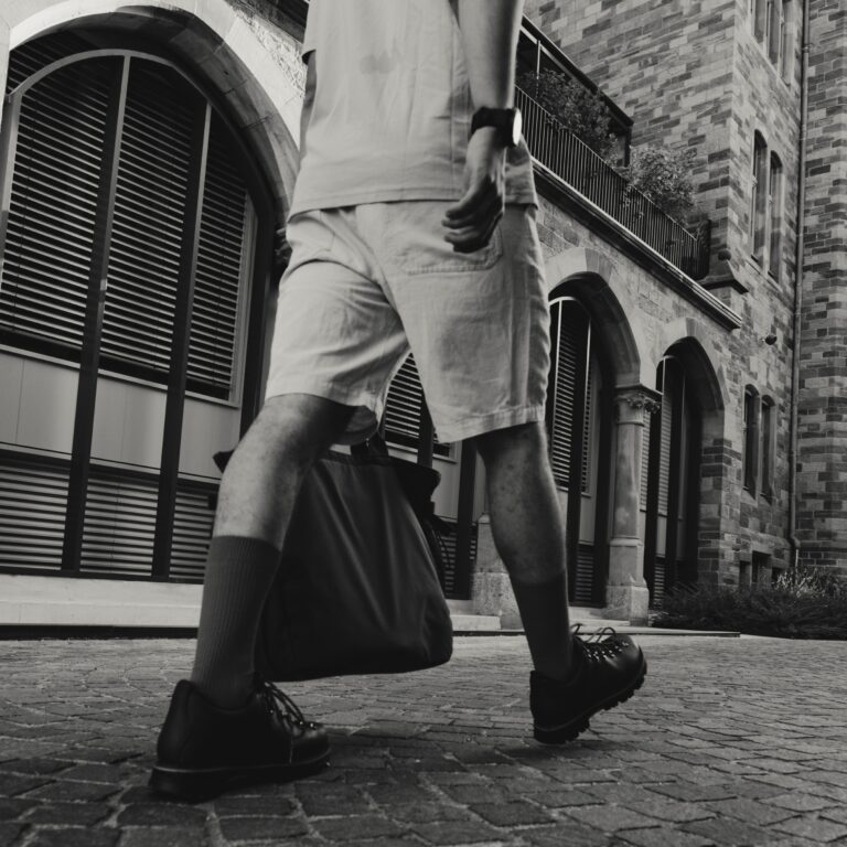 Silhouette floue d'un marcheur urbain portant des chaussures de marche urbaine Galibier en cuir avec lacets rouges et chaussettes rouges, style urbain décontracté.