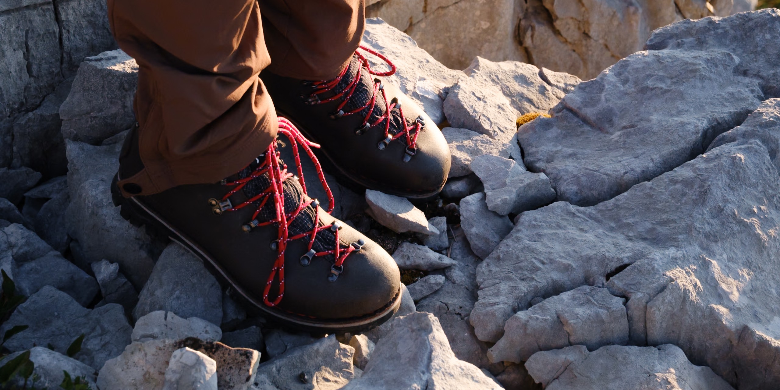 Gros plan de chaussures trekking femme Galibier en cuir marron et lacets rouges sur le calcaire du Parmelan.