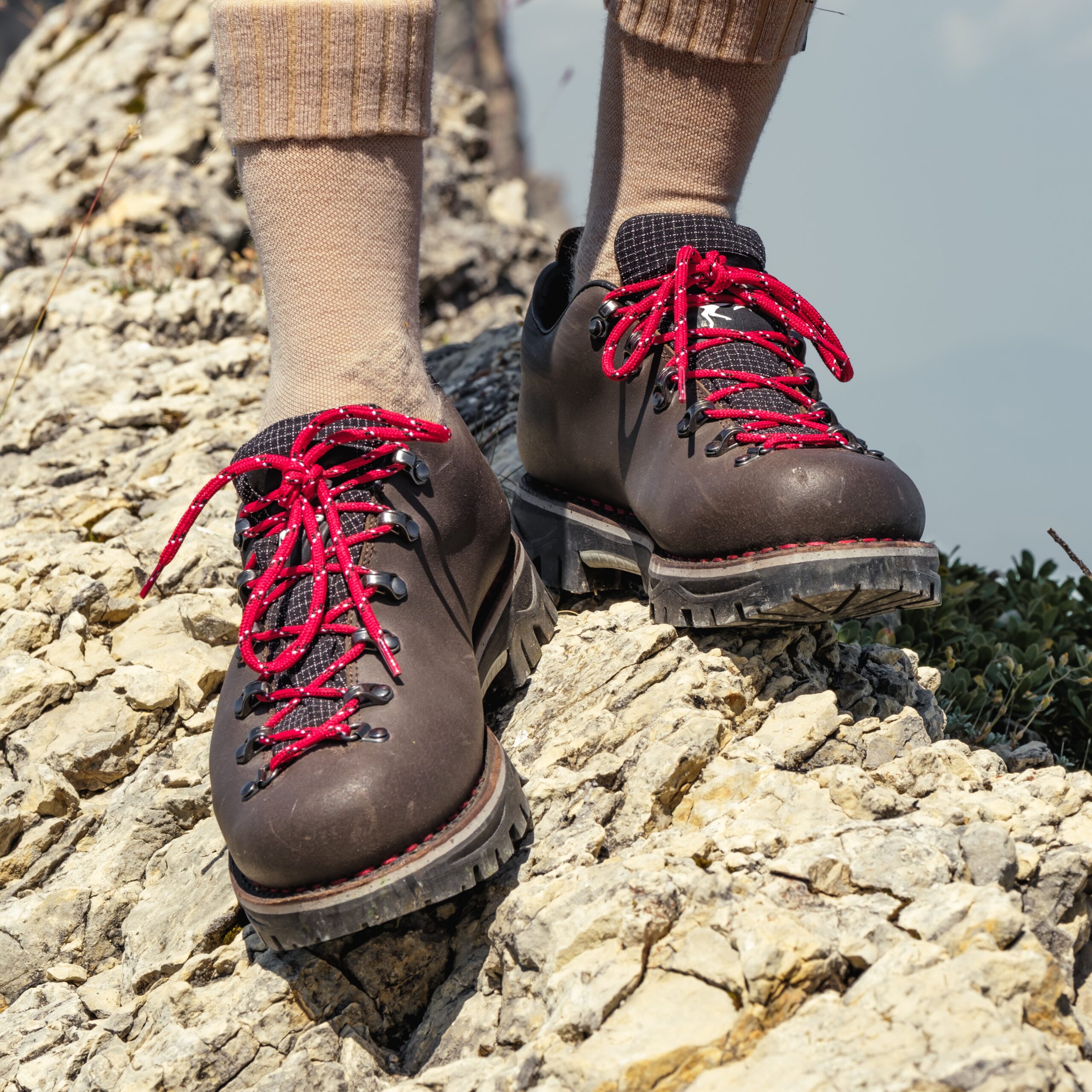 Chaussures trekking homme tige basse en cuir marron avec lacets rouges Galibier en appui sur une crête rocheuse.