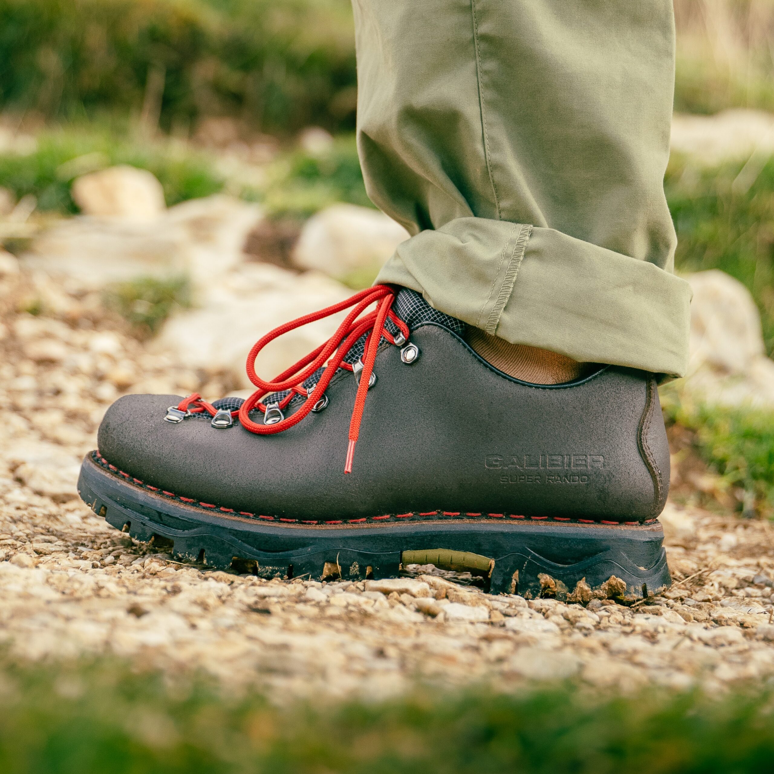 Gros plan de profil de la chaussure outdoor femme tige basse Galibier Super Rando Low en cuir marron avec lacets rouges sur un sentier de graviers.