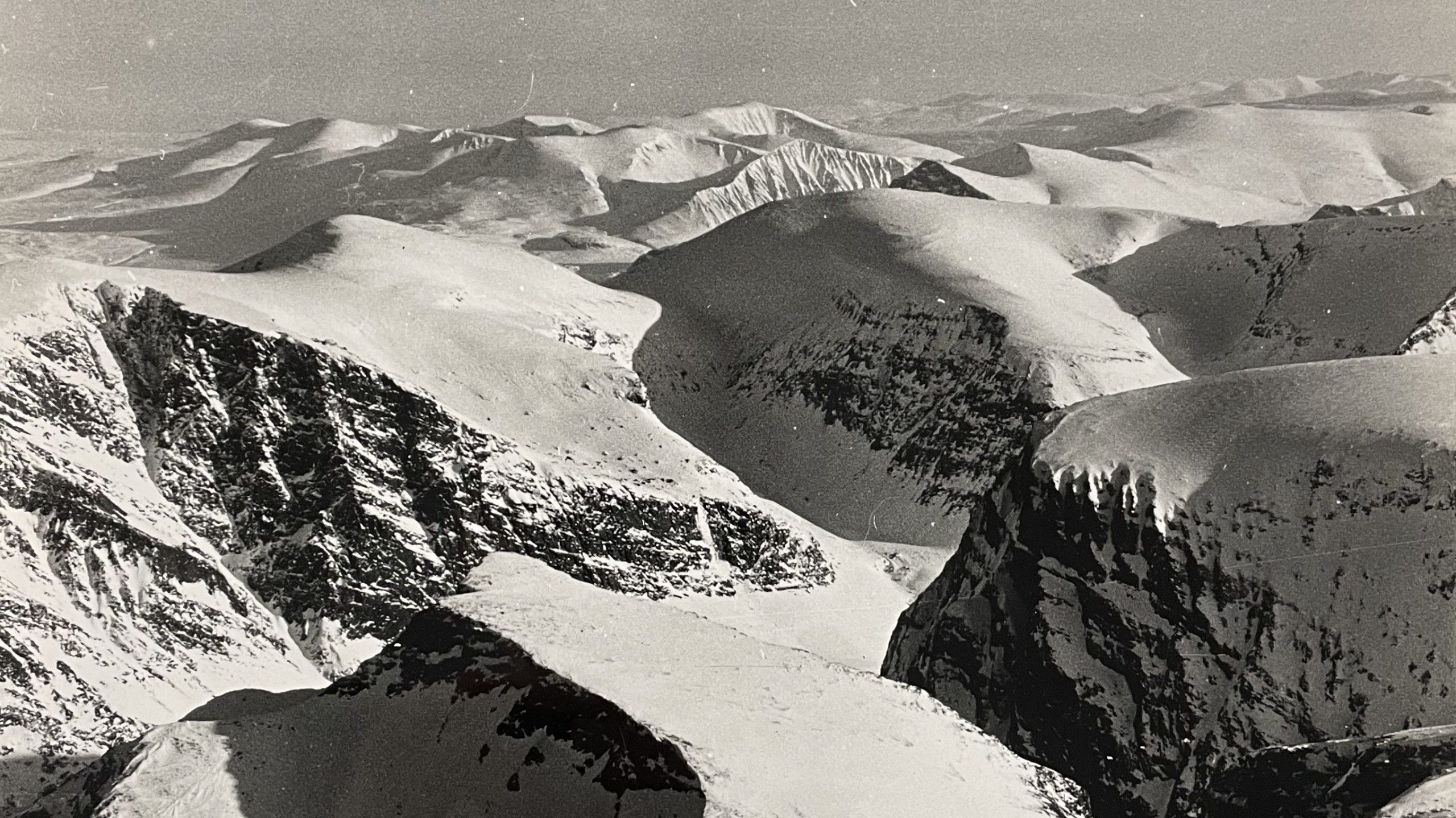 Vue aérienne argentique de crêtes rocheuses et de sommets enneigés en haute montagne.